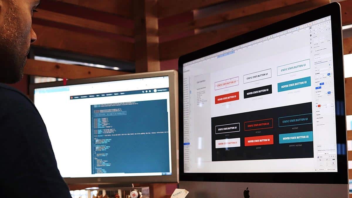 Photo montrant un développeur web devant un double-écran en train d'intégrer les éléments d'un site internet en cours de création
