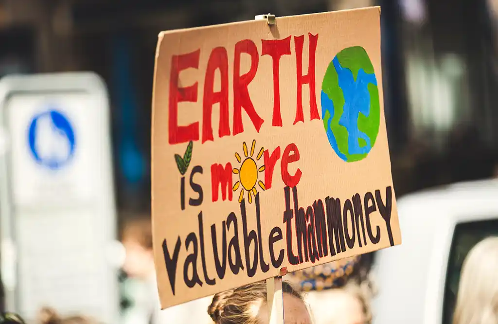 Photo montrant une pancarte sur laquelle il est écrit Earth is more valuable than money