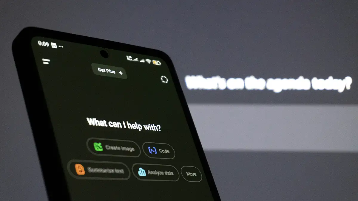 Smartphone à gauche de l'image avec écréan d'accueil ChatGPT et message What can I help with…