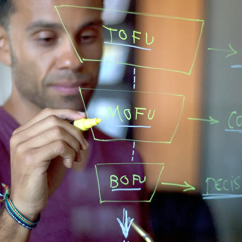Photo montrant un homme au travers d'une glace sur laquelle il écrit TOFU MOFU BOFU avec un feutre jaune